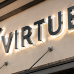 Professional installers mounting illuminated channel letter signs on a commercial storefront in Fort Myers.