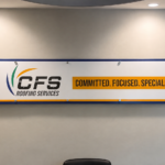 Custom CFS Roofing Services lobby sign installed in a Cape Coral meeting room with professional branded graphics.