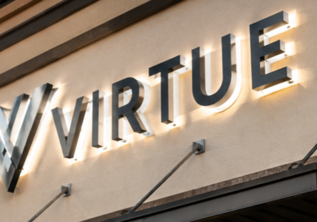 Professional installers mounting illuminated channel letter signs on a commercial storefront in Fort Myers.
